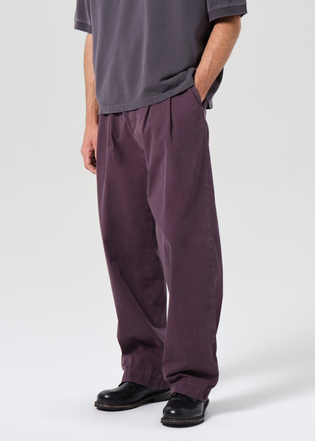 Person wearing a gray shirt and purple pants on a white background