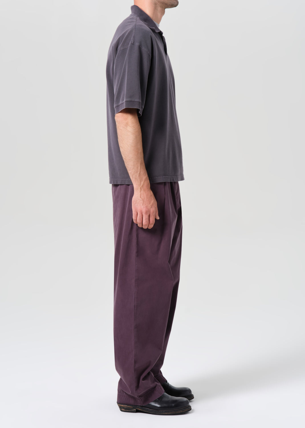 Person wearing a gray shirt and purple pants on a white background