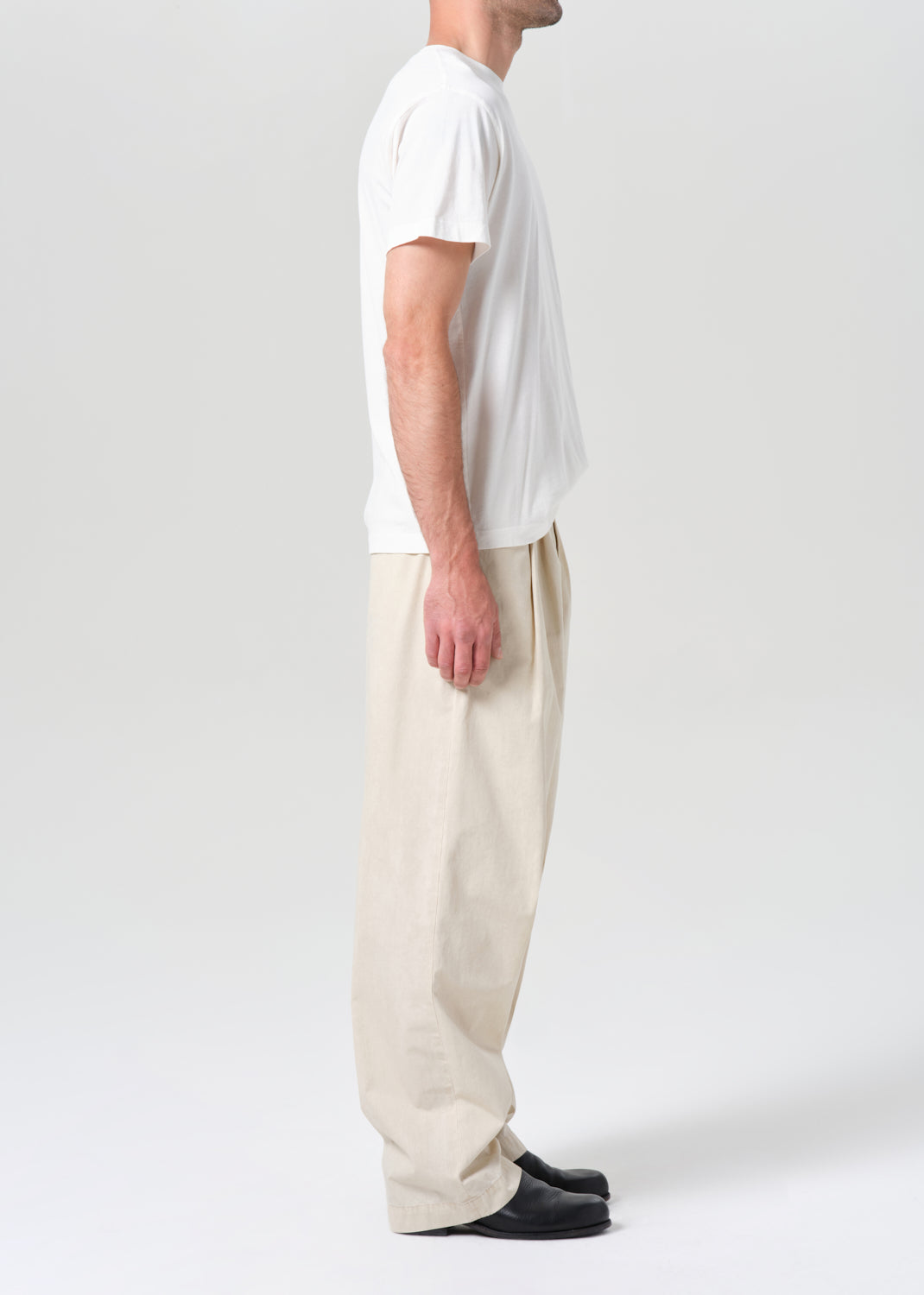Person wearing a white t-shirt and beige pants on a plain background