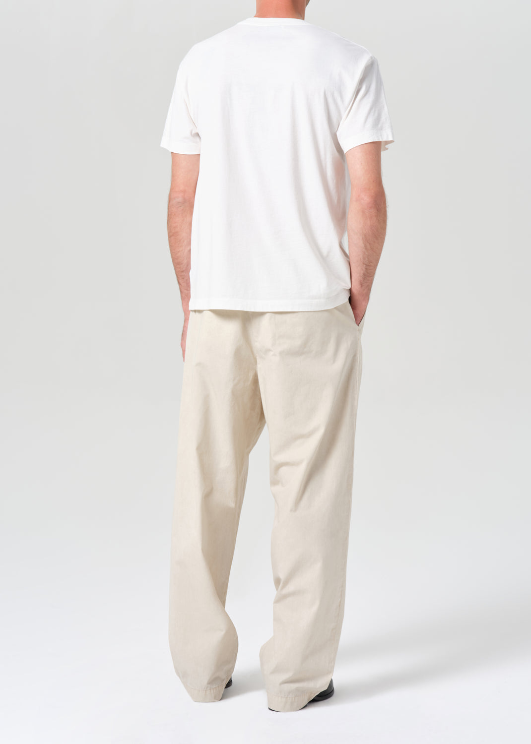 Person wearing a white t-shirt and beige pants on a plain background