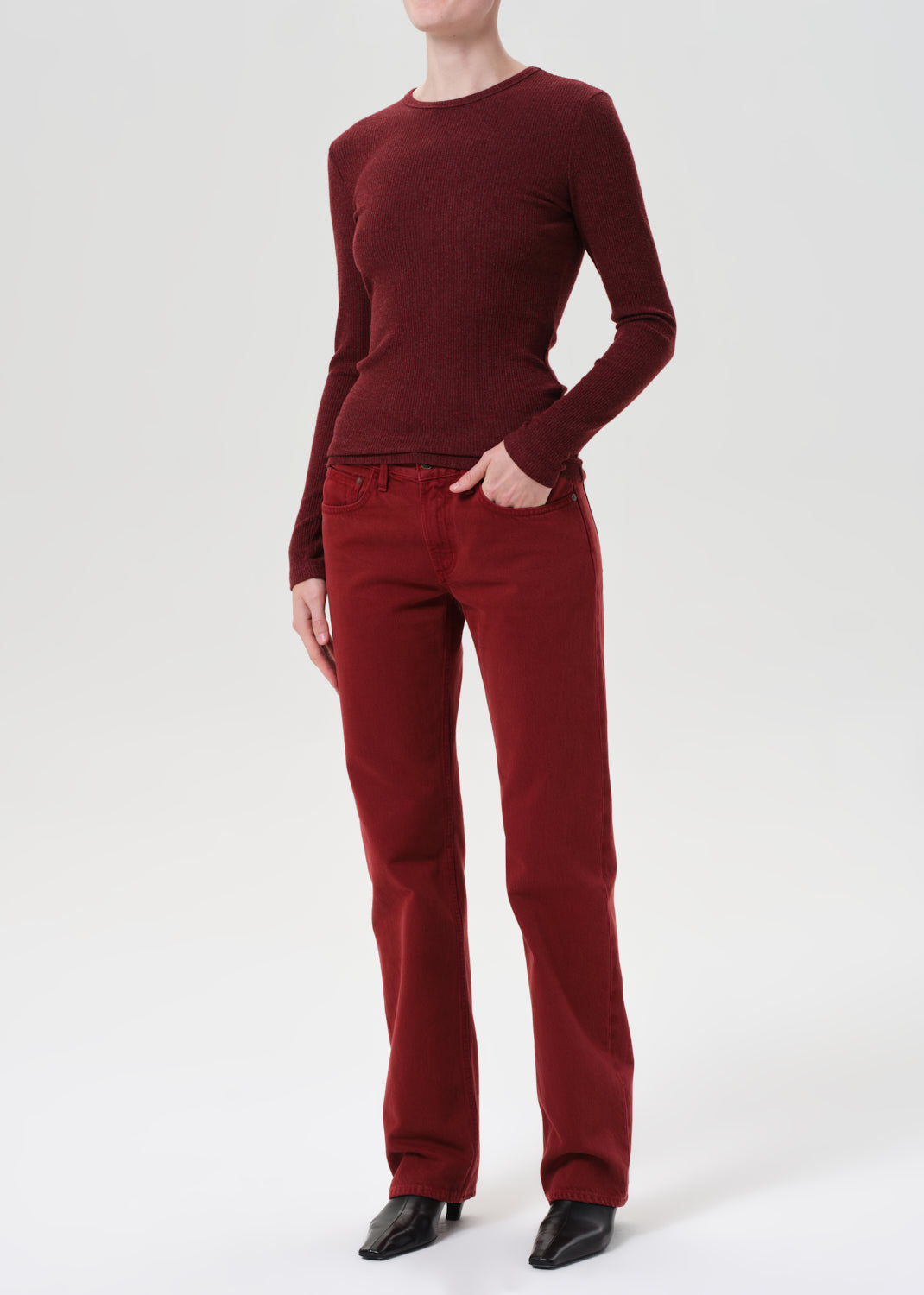 Person wearing a burgundy sweater and pants on a white background