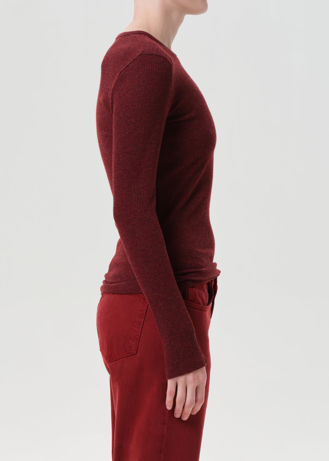 Person wearing a burgundy long-sleeve top and pants on a light gray background