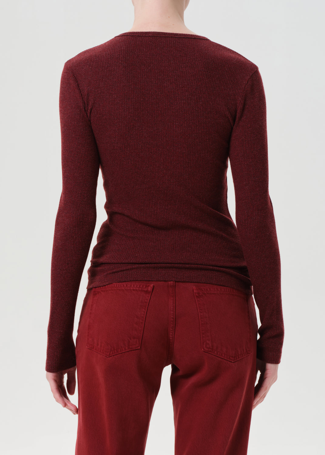 Person wearing a burgundy sweater and pants on a white background