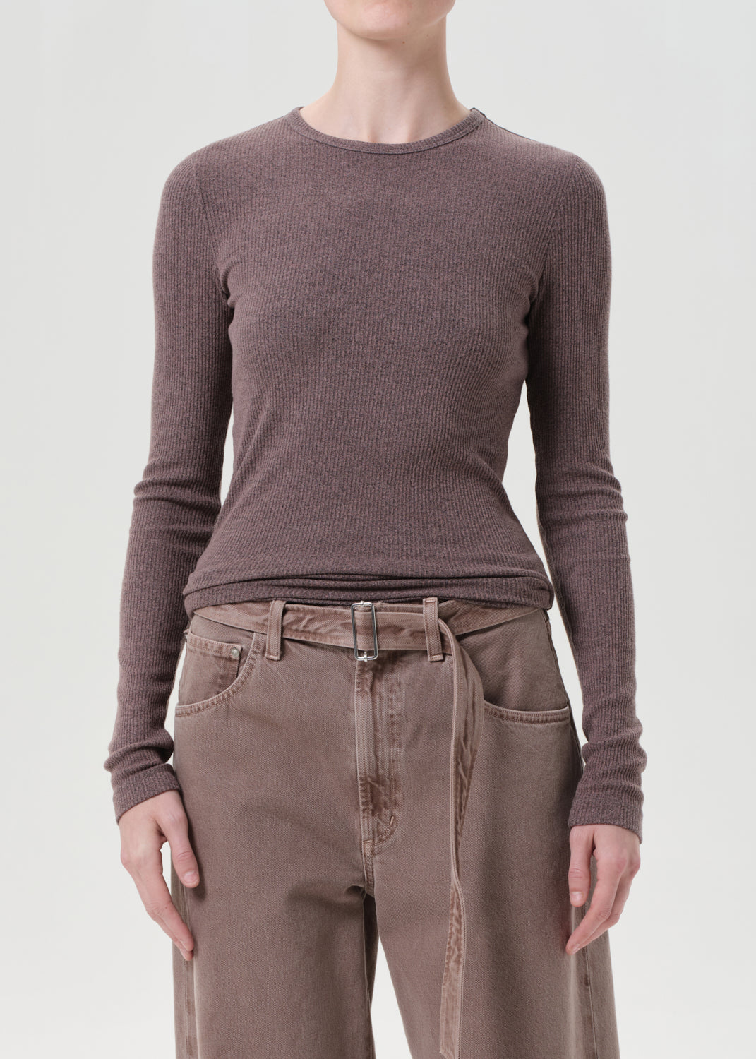 Person wearing a brown long-sleeve shirt and brown pants on a white background