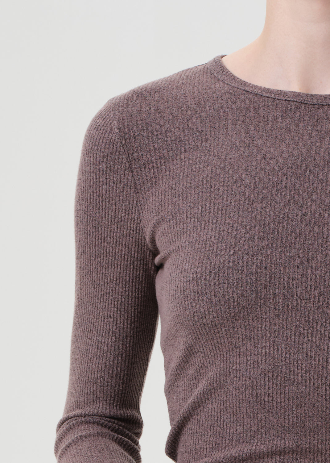 Close-up of a brown ribbed sweater on a mannequin against a light gray background