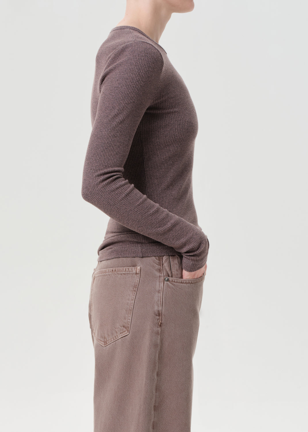Person wearing a brown sweater and pants on a light gray background