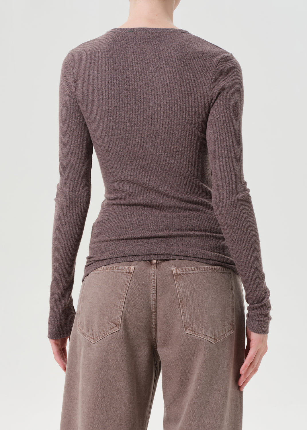 Person wearing a brown sweater and pants on a white background