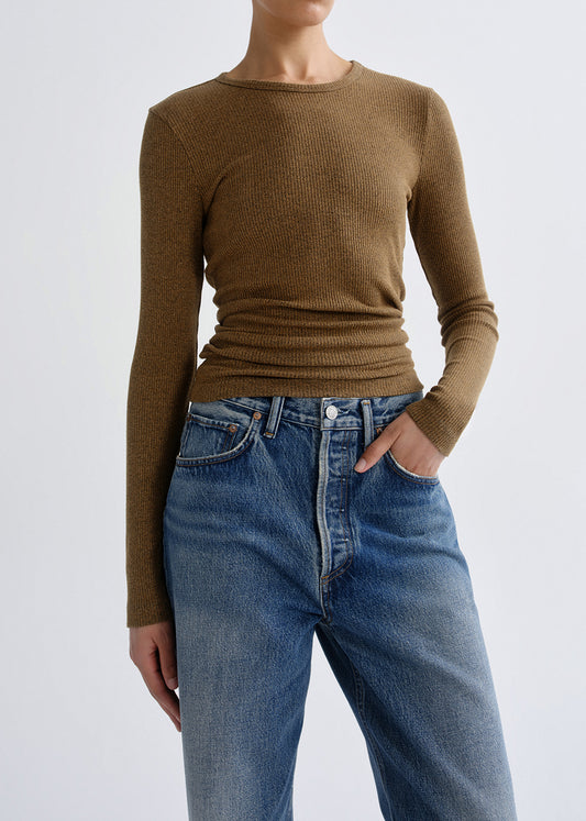 Person wearing a brown long sleeve crewneck top with light wash cuffed straight leg jeans on a grey background