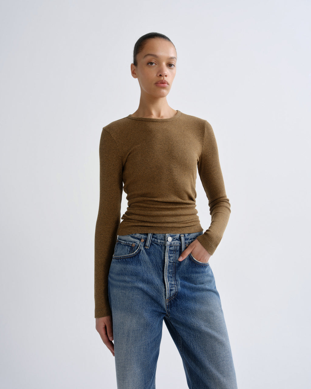Person wearing a brown sweater and blue jeans on a white background