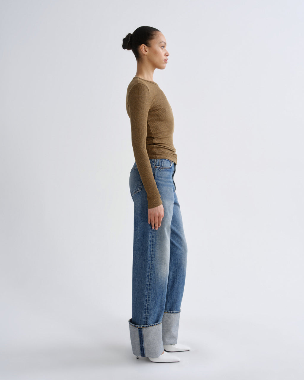 Person wearing a brown top and blue jeans on a white background