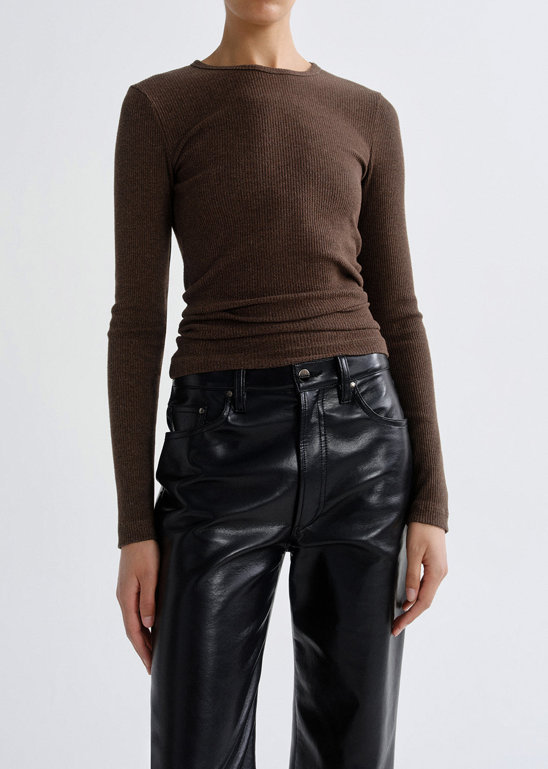 Person wearing a brown long sleeve ribbed top on a grey background.