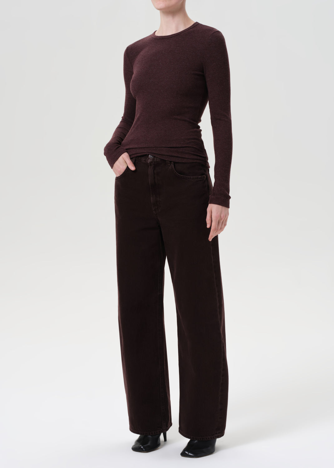 Person wearing a brown long-sleeve top and wide-leg pants on a white background
