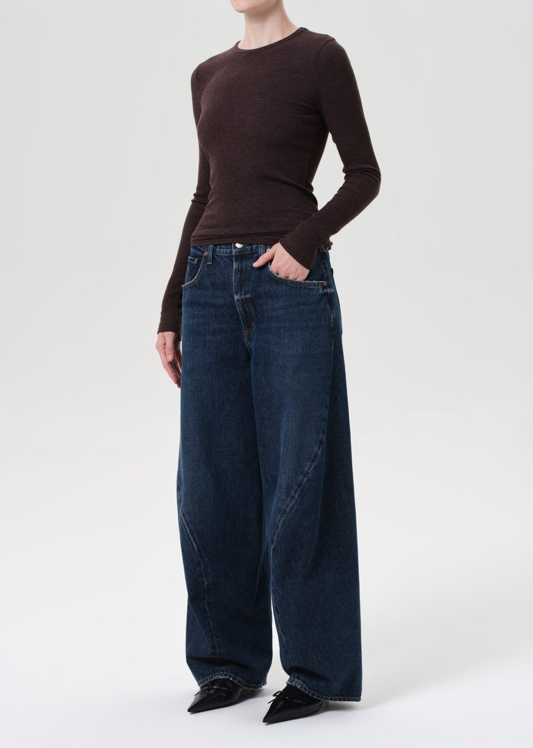 Person wearing a brown sweater and blue jeans on a white background