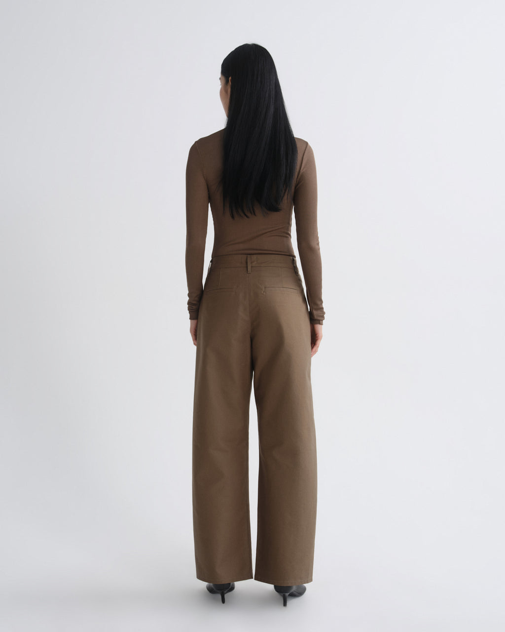 Woman wearing a brown jumpsuit on a white background