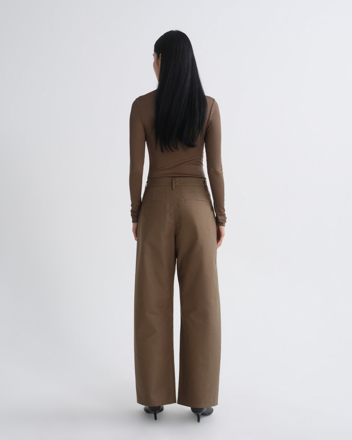 Woman wearing a brown jumpsuit on a white background