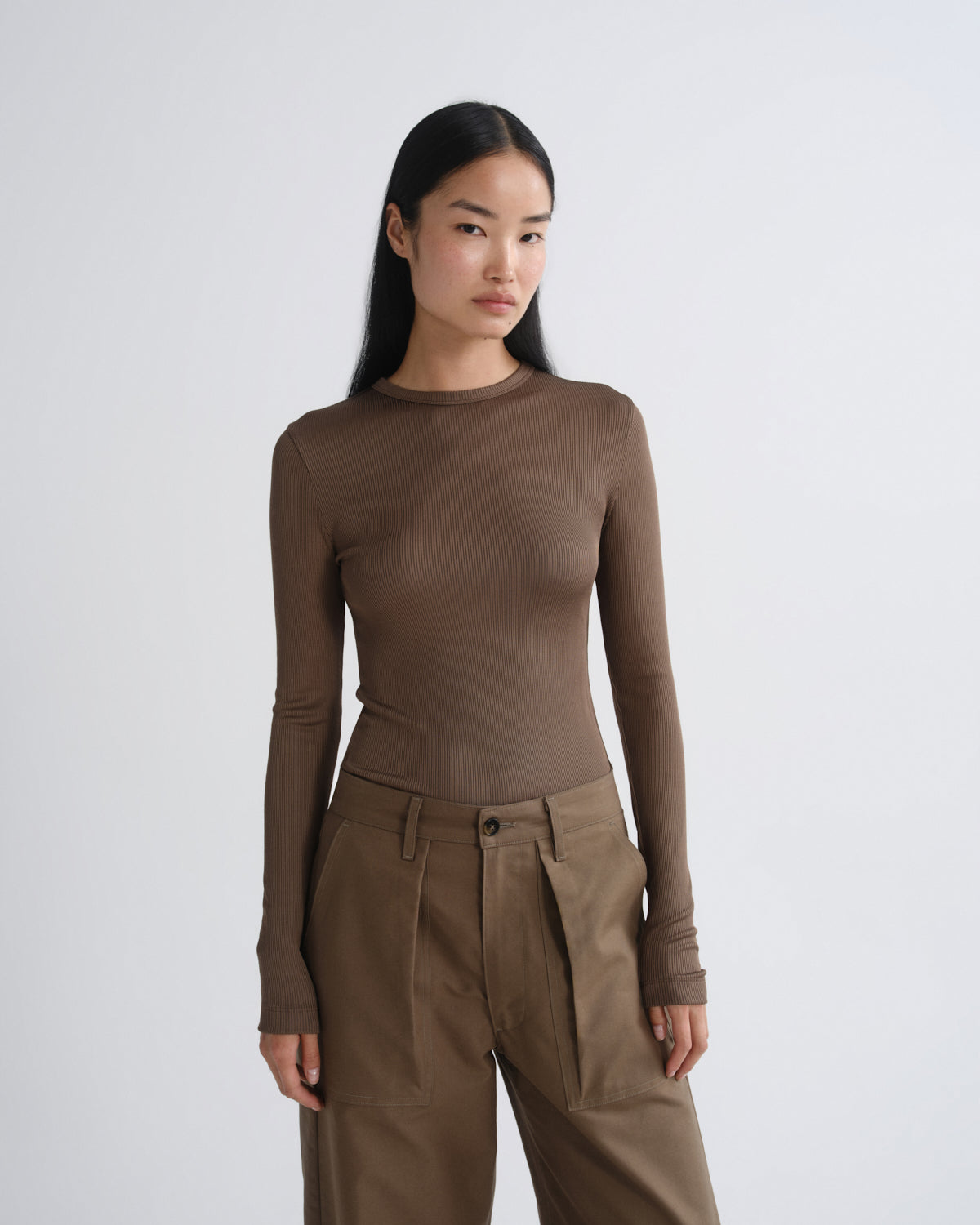 Woman wearing a brown long-sleeve top and pants on a white background