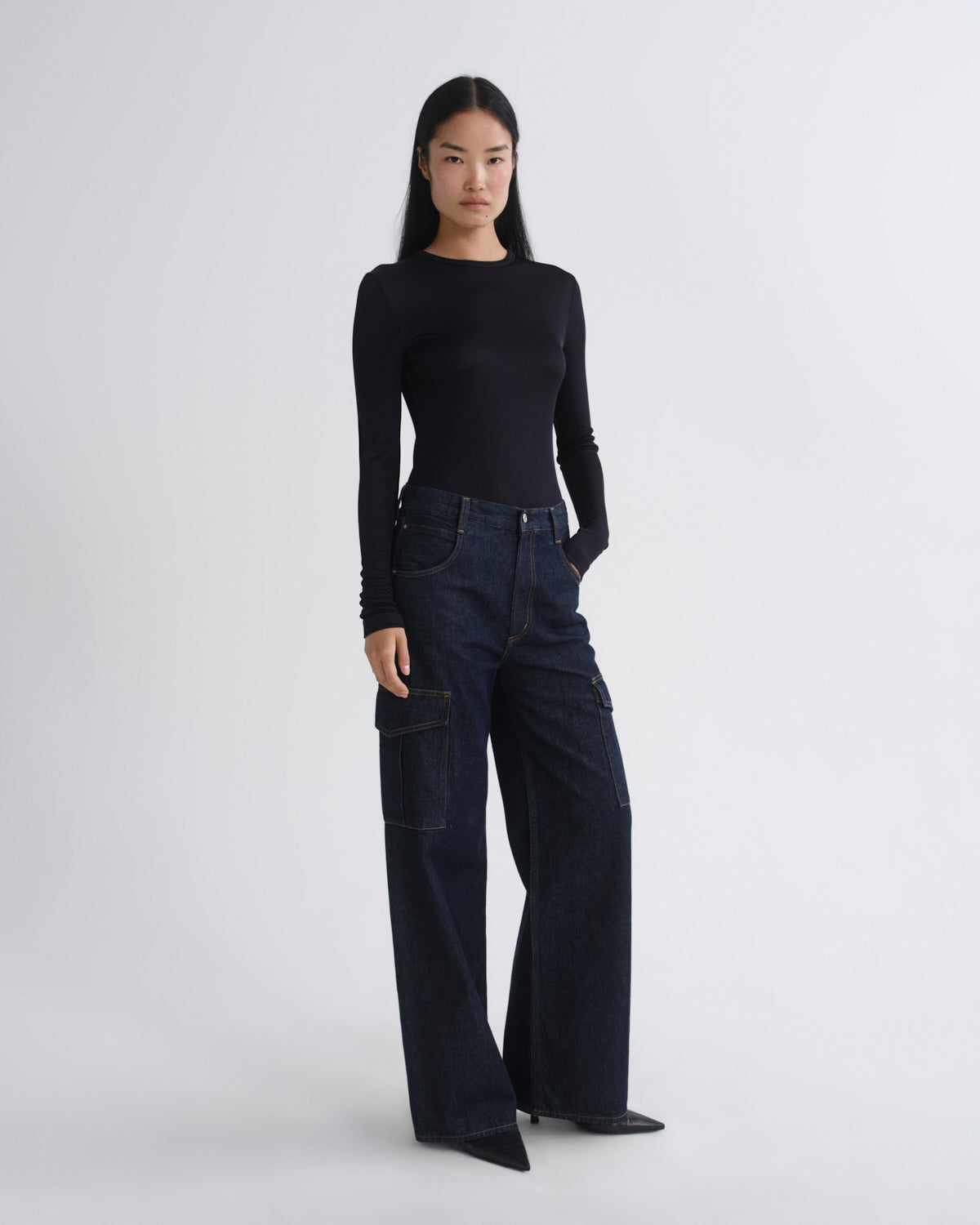 Person wearing a black long-sleeve top and dark blue jeans on a white background