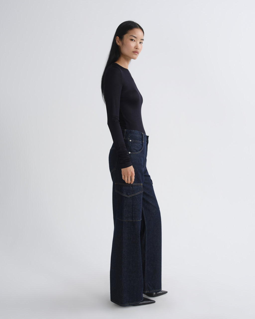 Person wearing a black top and dark blue jeans on a white background