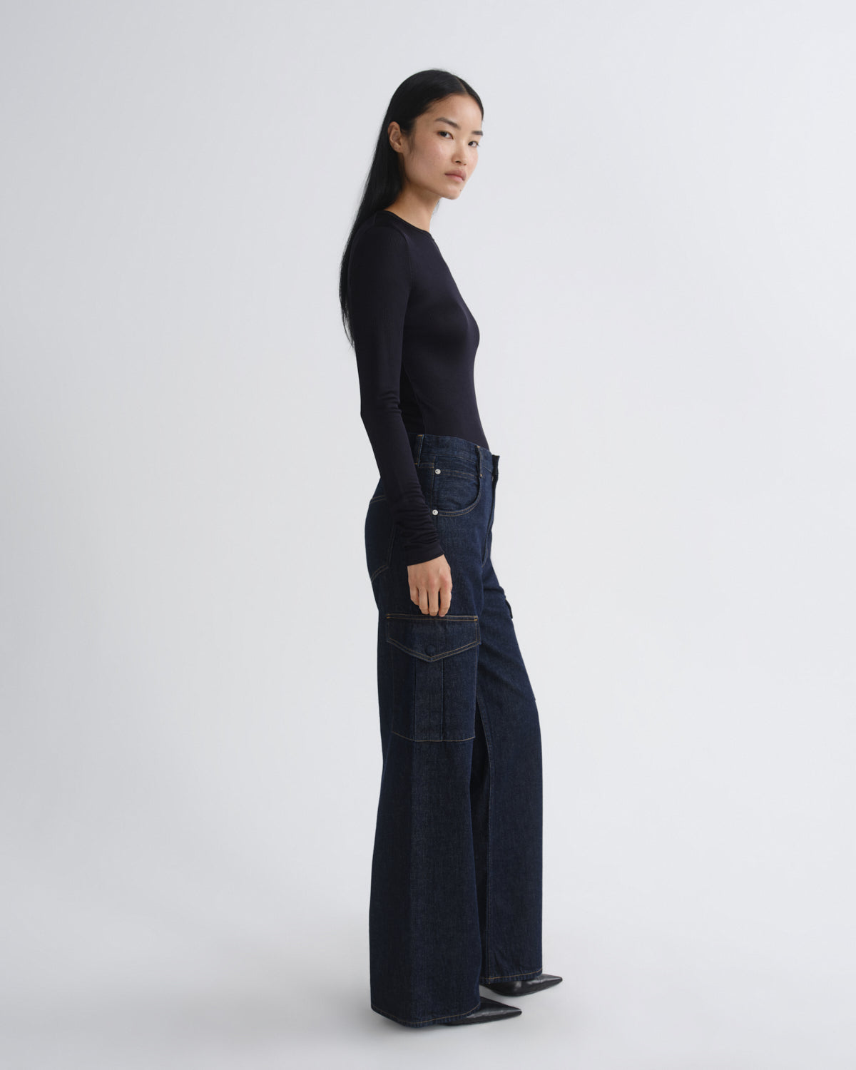 Person wearing a black top and dark blue jeans on a white background