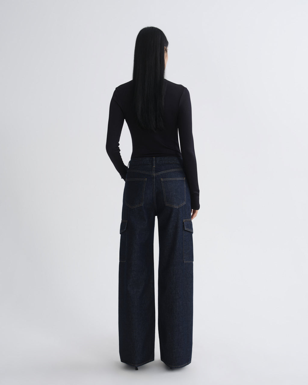 Person wearing dark blue cargo pants and a black top on a white background