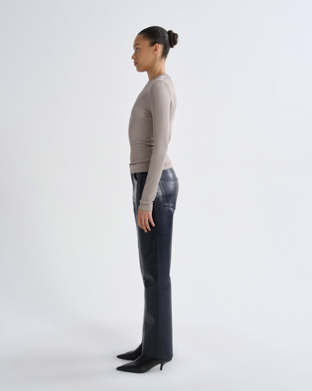Person wearing a beige sweater and black pants on a white background