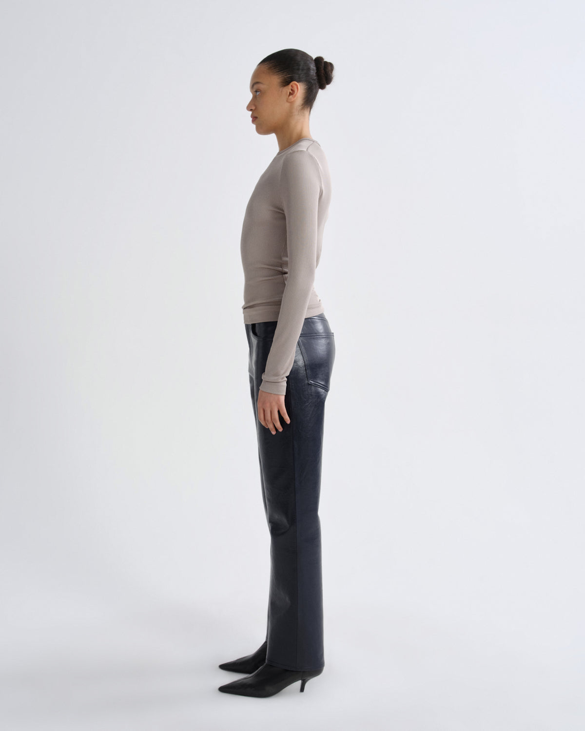 Person wearing a beige sweater and black pants on a white background