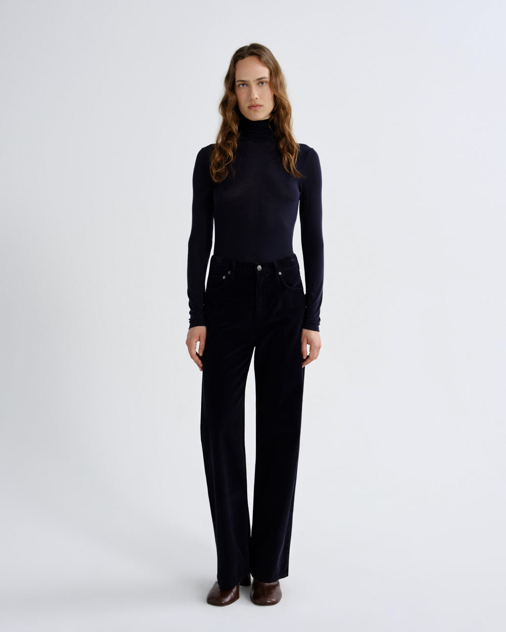 Woman wearing a black turtleneck and black pants on a white background