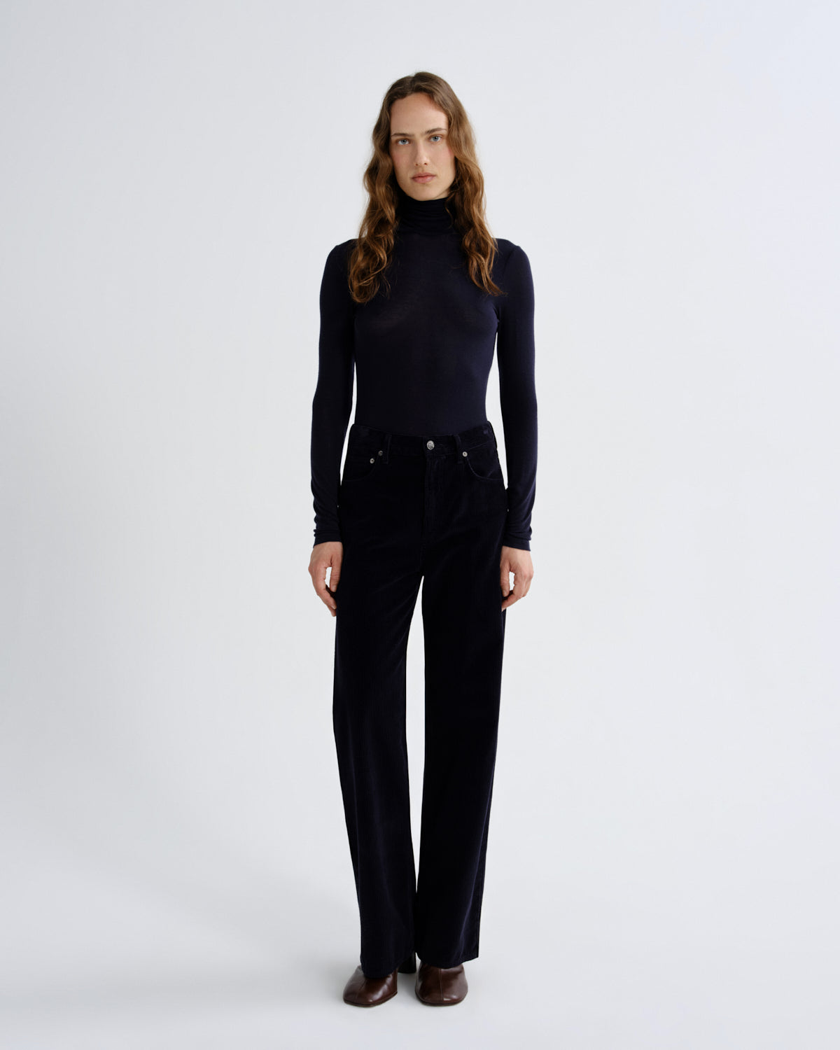 Woman wearing a black turtleneck and black pants on a white background