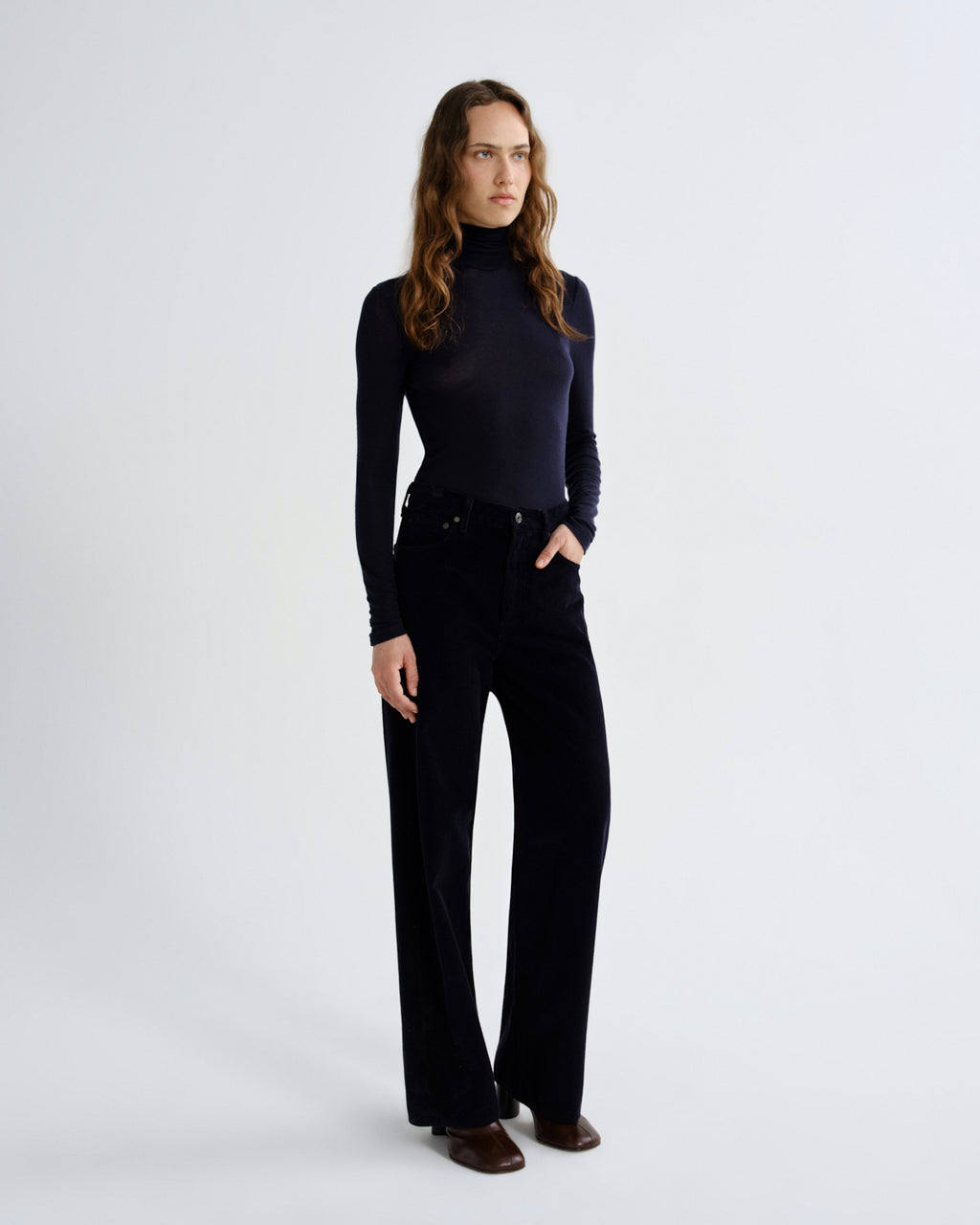 Woman wearing a black turtleneck and black pants on a white background