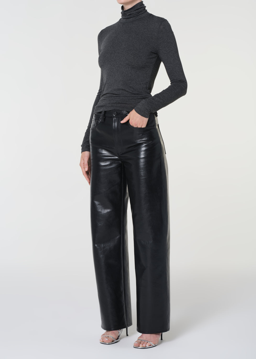 Person wearing a black turtleneck and black leather pants on a white background