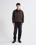 Person wearing a brown sweater and black pants on a white background