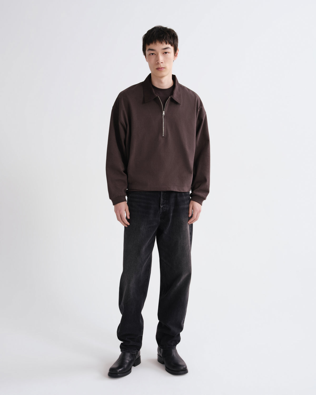 Person wearing a brown sweater and black pants on a white background