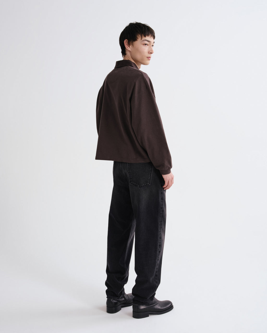 Person wearing a brown shirt and black pants on a white background