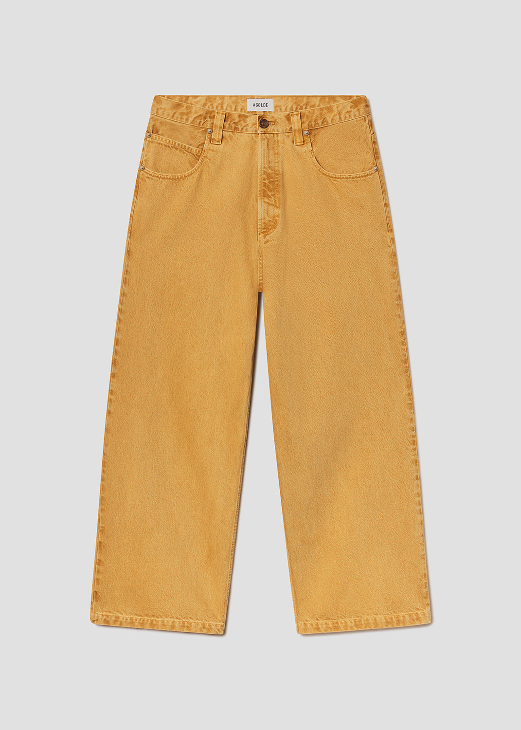 Flat lay of mustard yellow jeans on a grey background