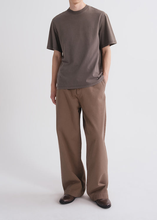 Person wearing a brown shirt and brown pants on a grey background