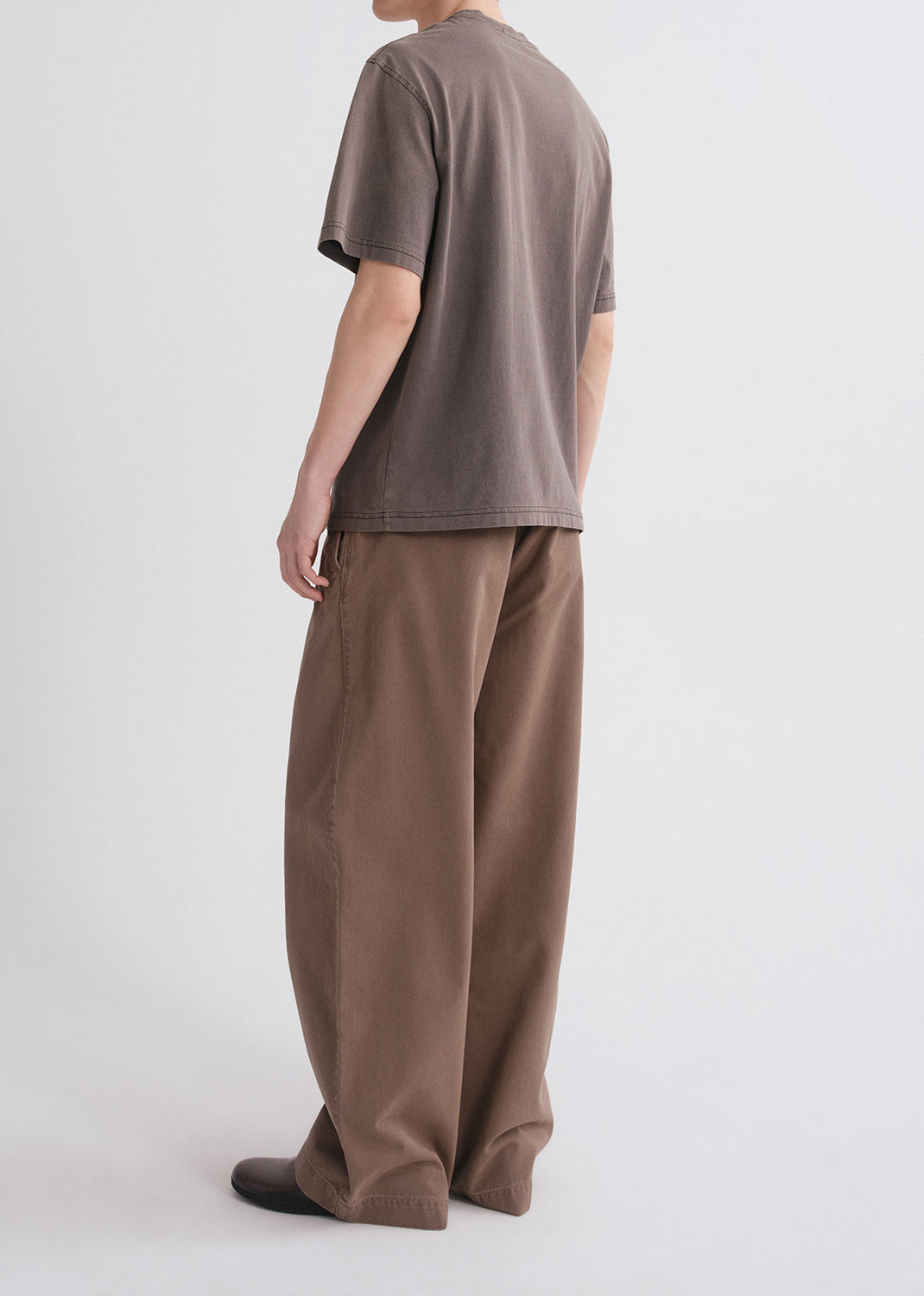 Person wearing a brown shirt and brown pants on a grey background