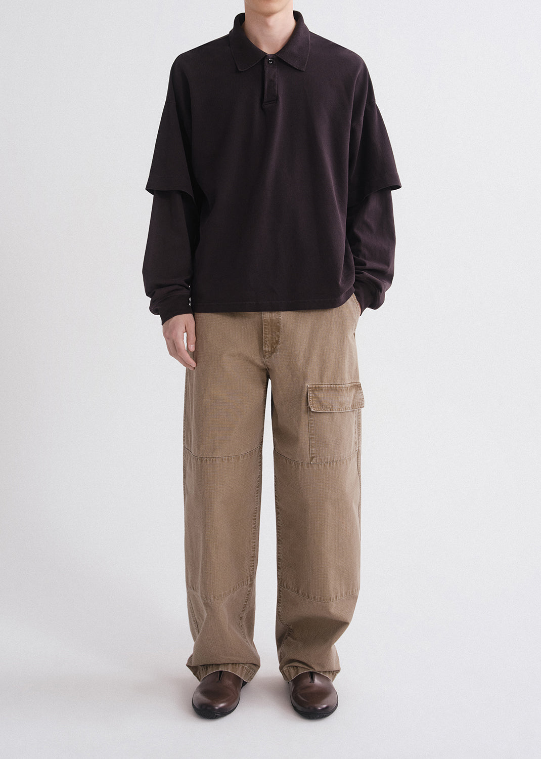 Person wearing a dark brown long-sleeve shirt and beige cargo pants on a grey background