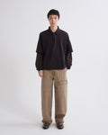 Person wearing a black shirt and brown pants on a white background