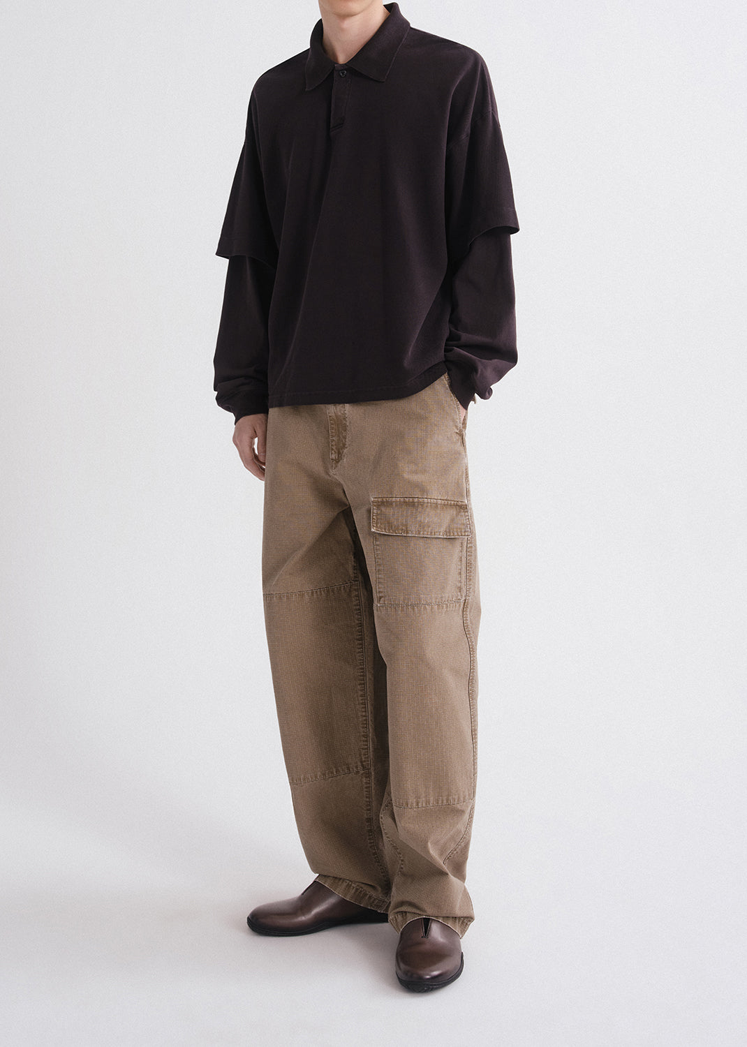 Person wearing a black shirt and brown cargo pants on a grey background