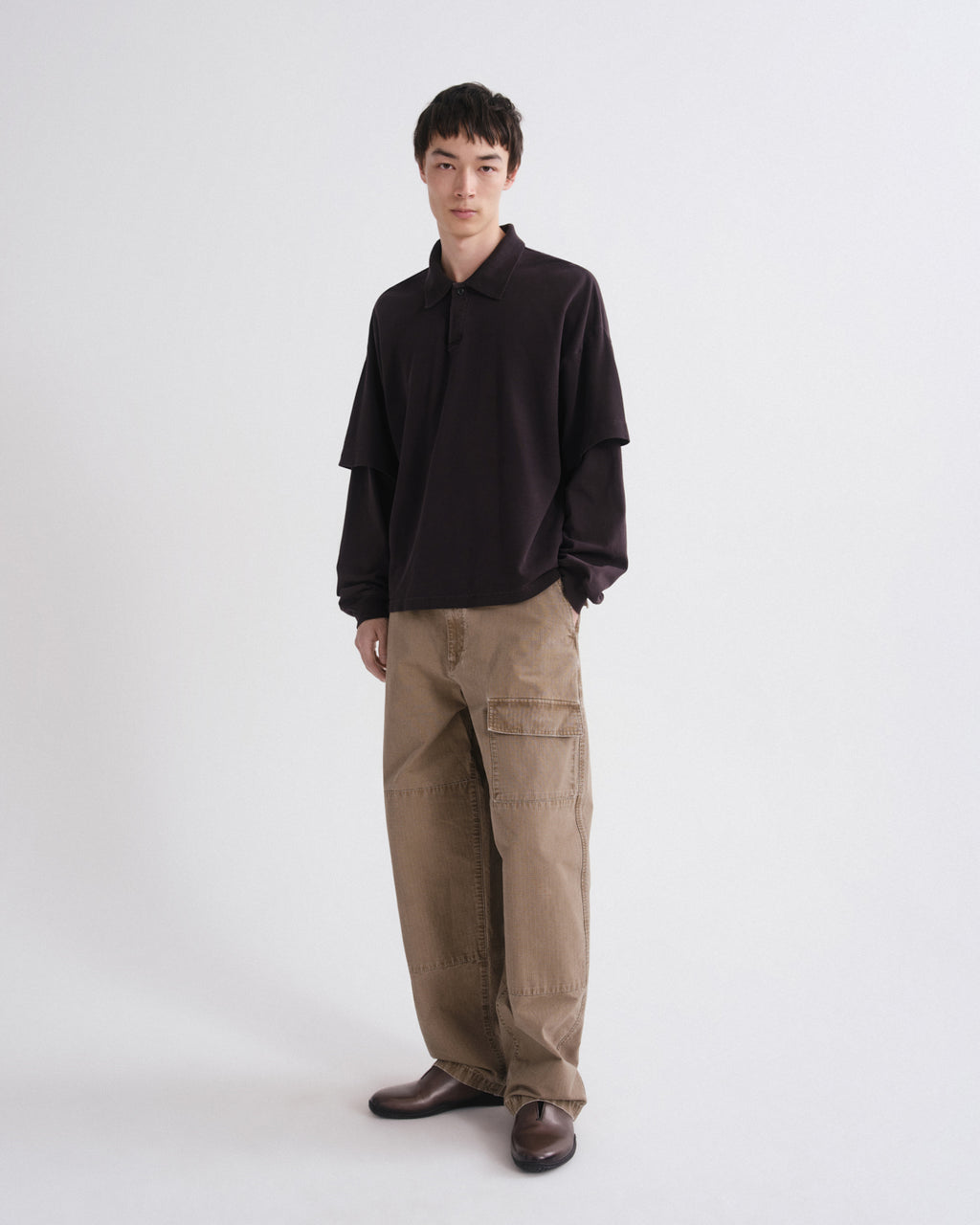 Person wearing a black shirt and brown pants on a white background