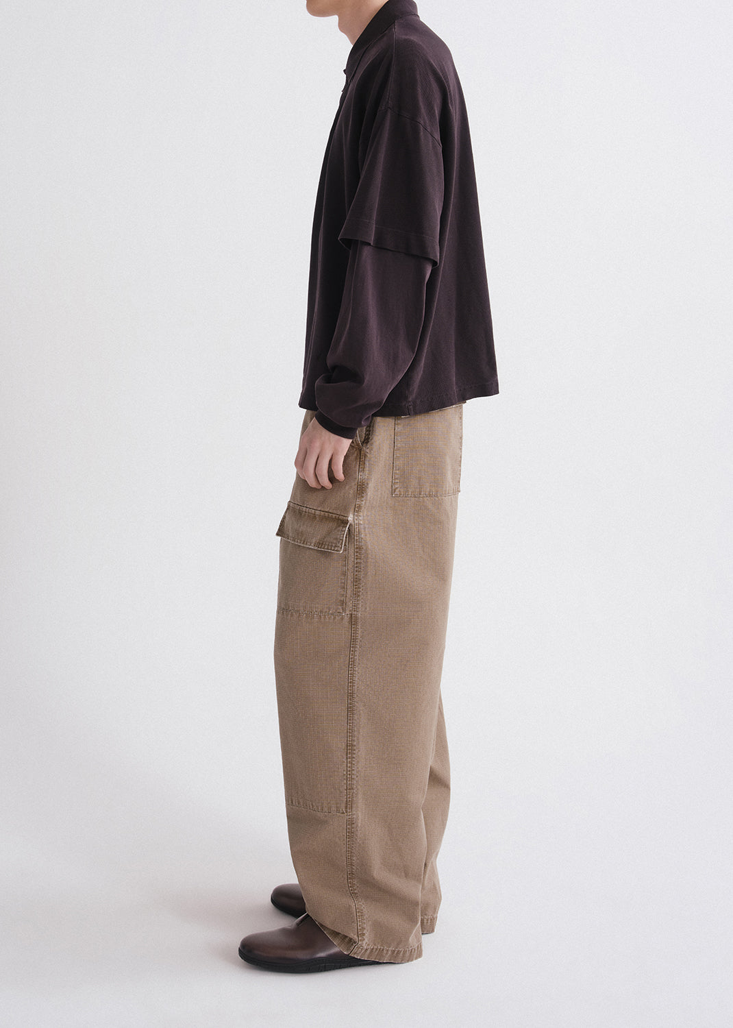 Person wearing a dark shirt and beige cargo pants on a grey background