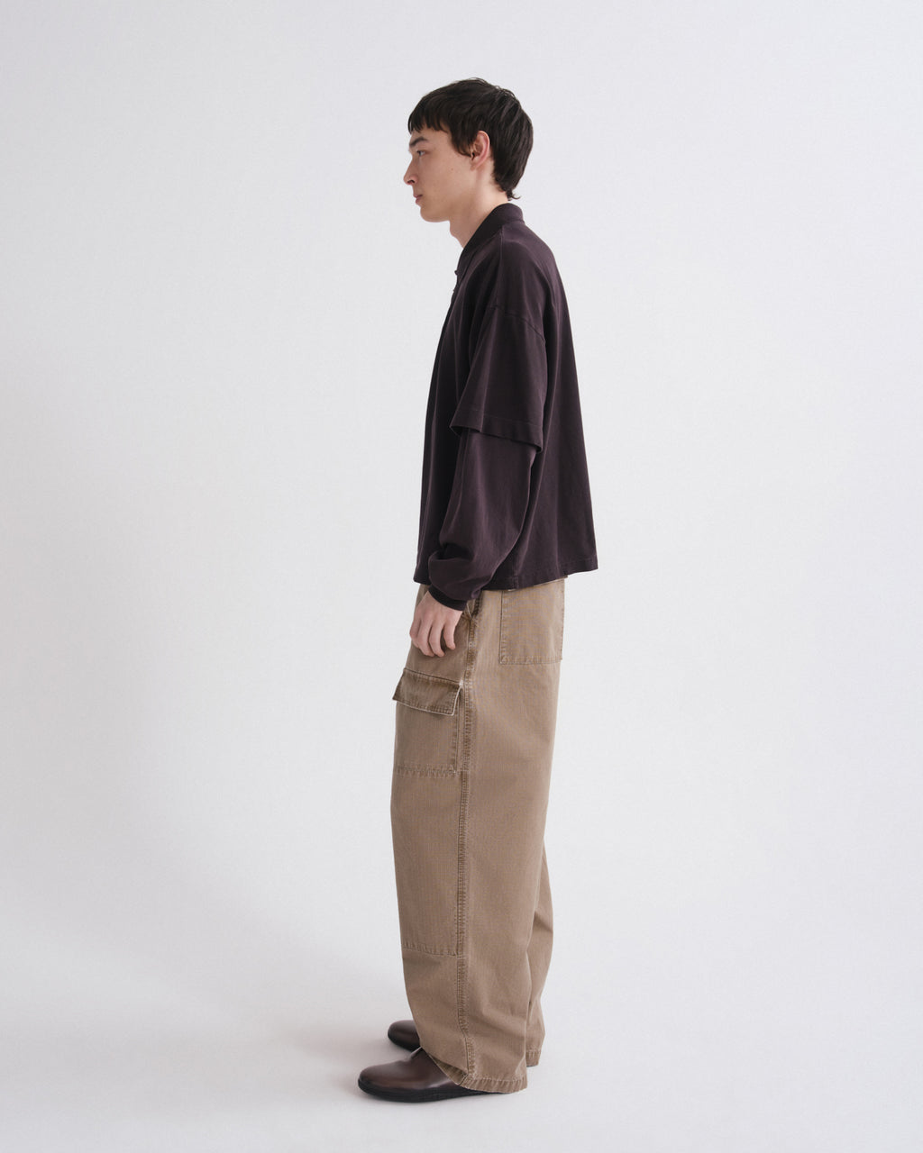 Person wearing a dark jacket and beige pants on a white background