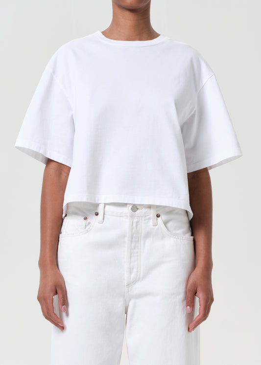 Person wearing a white t-shirt and white pants on a plain background
