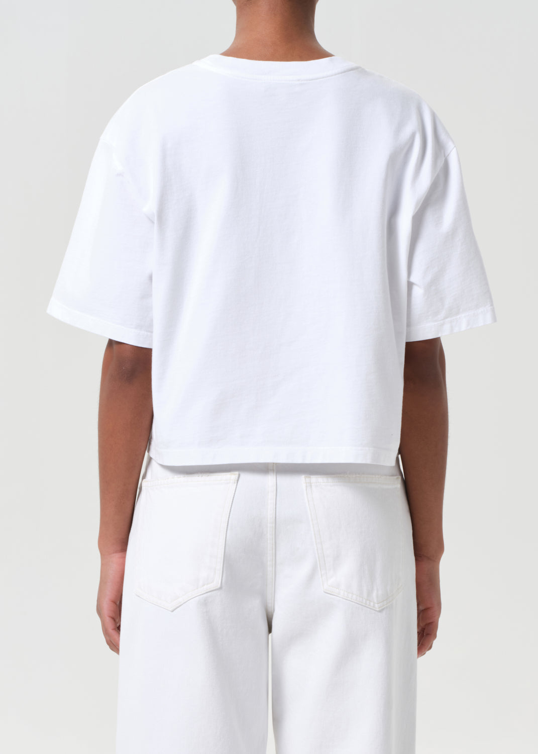 Person wearing a white t-shirt and pants on a plain background