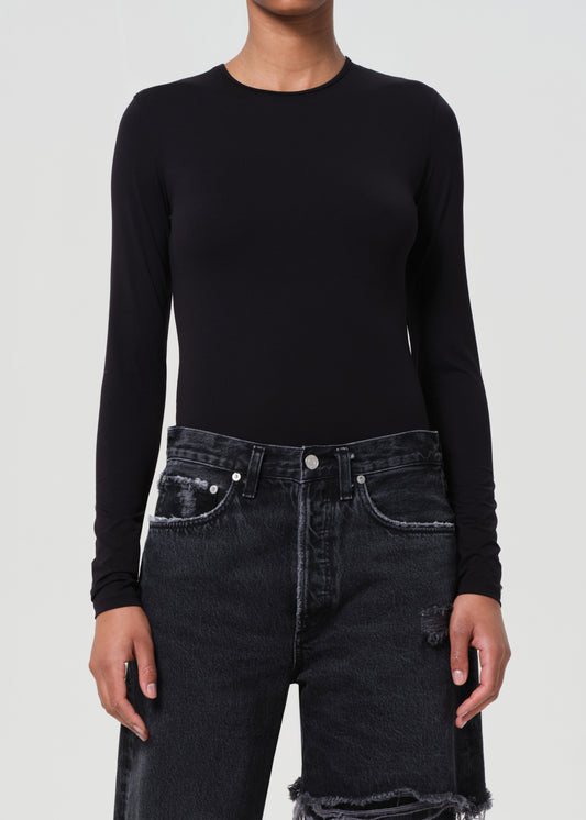 Person wearing a black long-sleeve top and black jeans on a white background