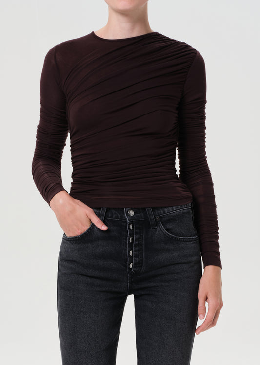 Person wearing a brown long-sleeve top and black jeans on a white background
