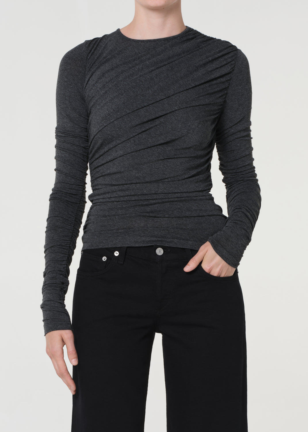 Person wearing a dark gray long-sleeve top and black pants on a white background