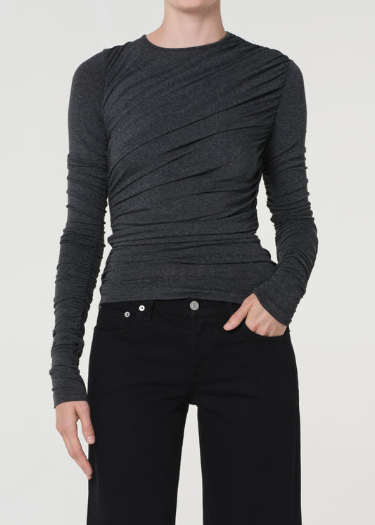 Person wearing a dark gray long-sleeve top and black pants on a white background