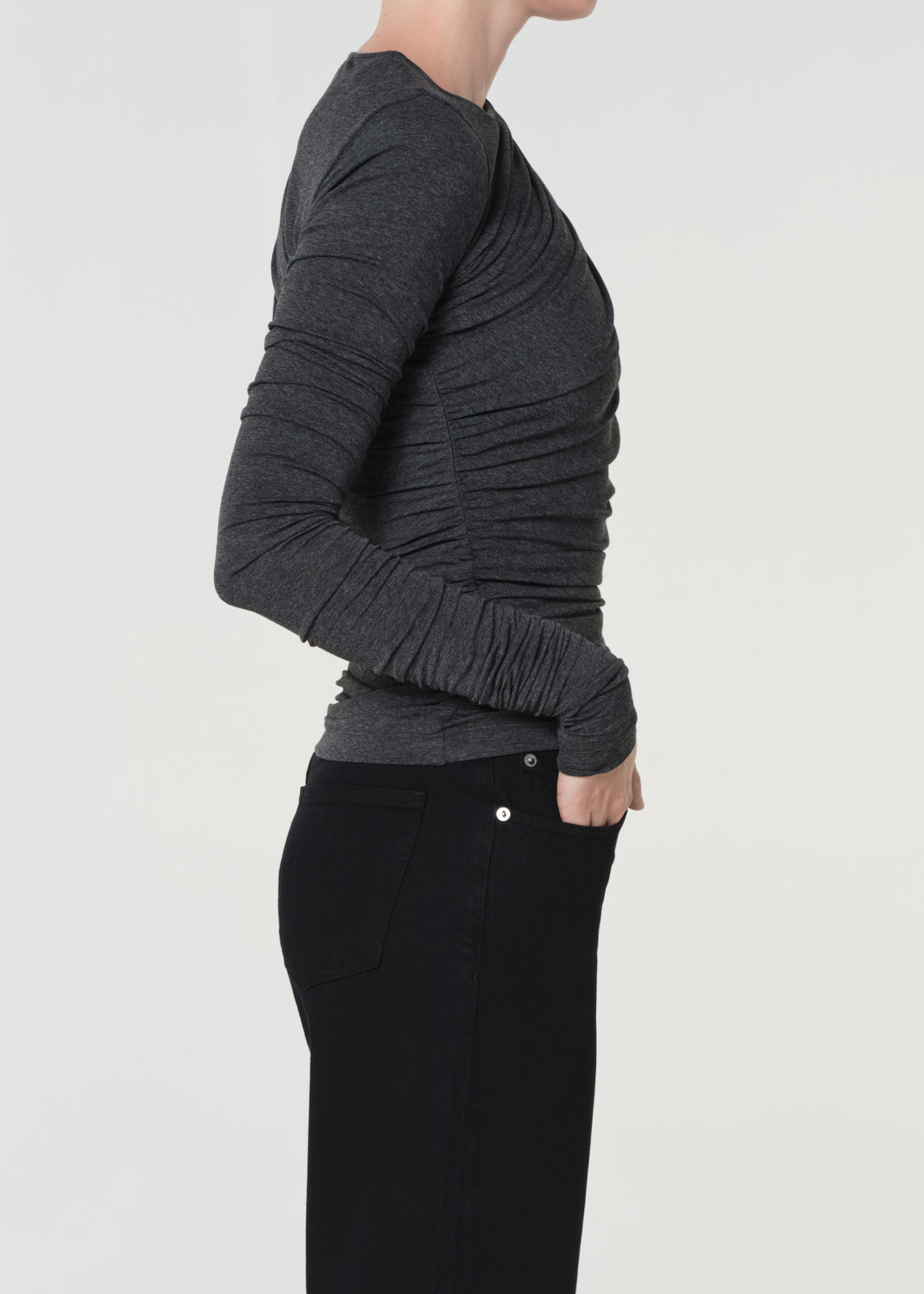 Person wearing a dark gray sweater and black pants on a light gray background