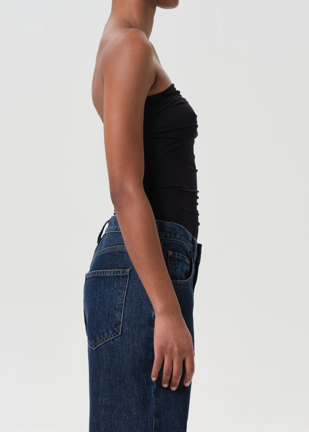 Person wearing a black top and blue jeans on a white background